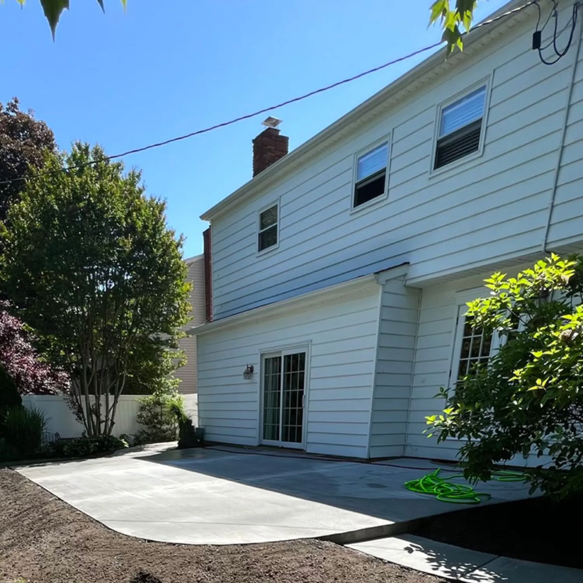 Large backyard concrete patio completed at white colonial home Cherry Hill NJ
