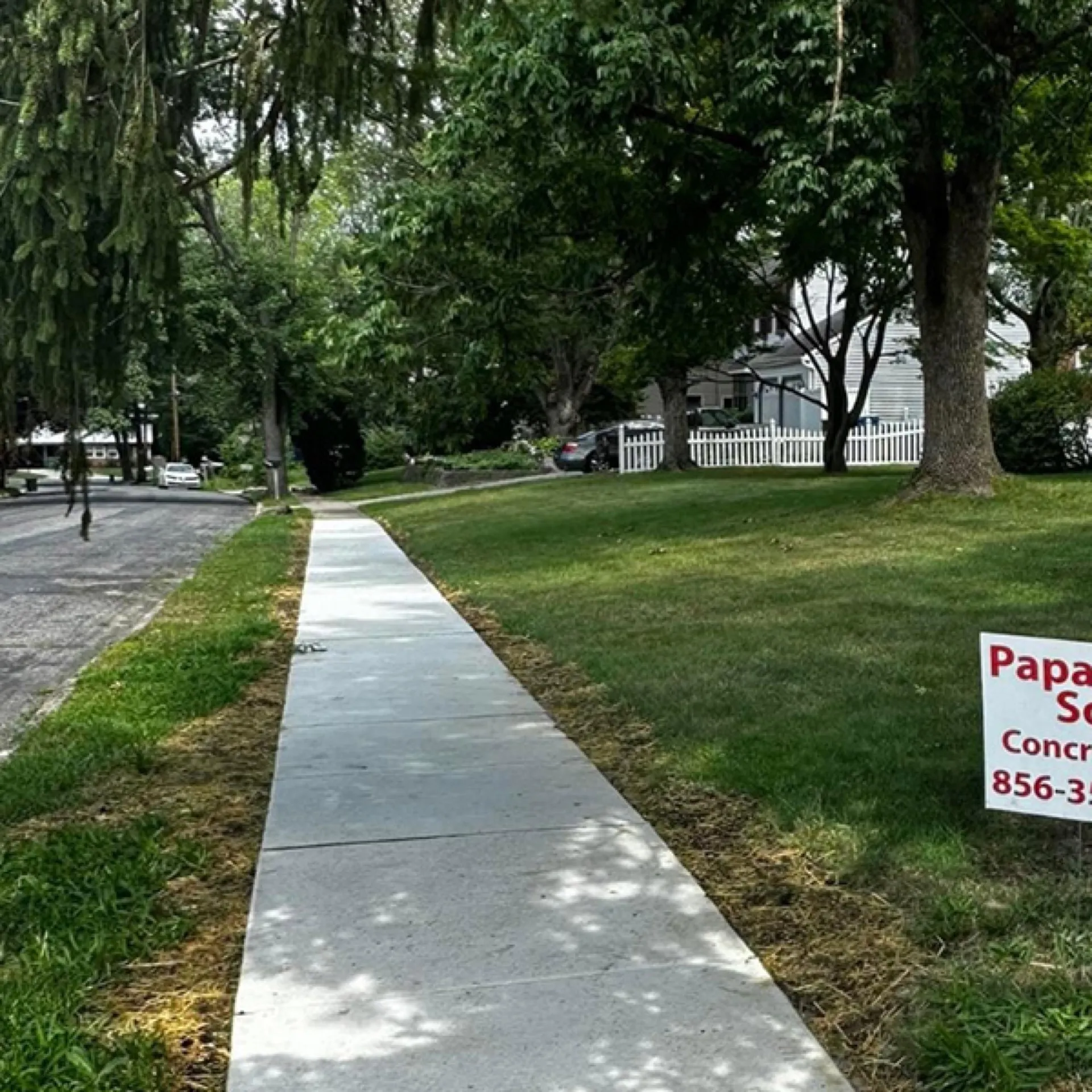Long residential concrete sidewalk installed along green lawn Cherry Hill NJ